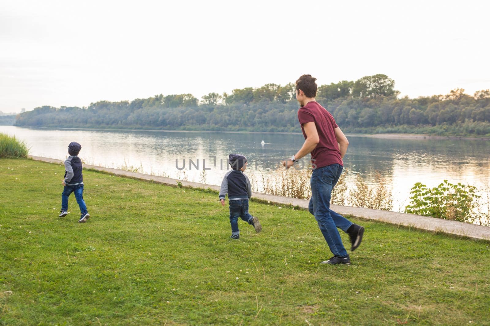 Childhood, family concept - father playing with two sons near the lake by Satura86