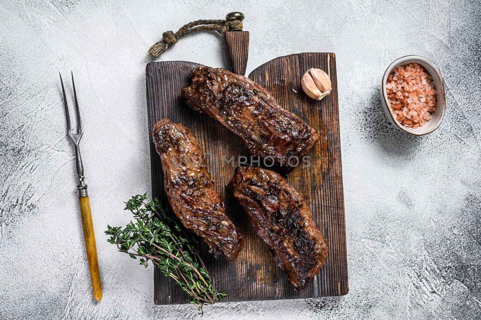 Grilled brisket steaks in bbq sauce on a wooden board. White background. Top view by Composter