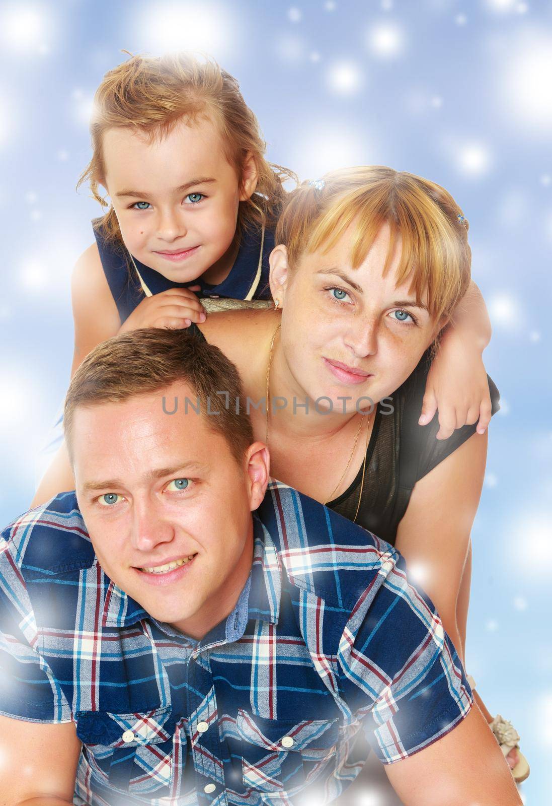 Cheerful young family of three. Mother and daughter lying on dad's back.Blue Christmas festive background with white snowflakes.