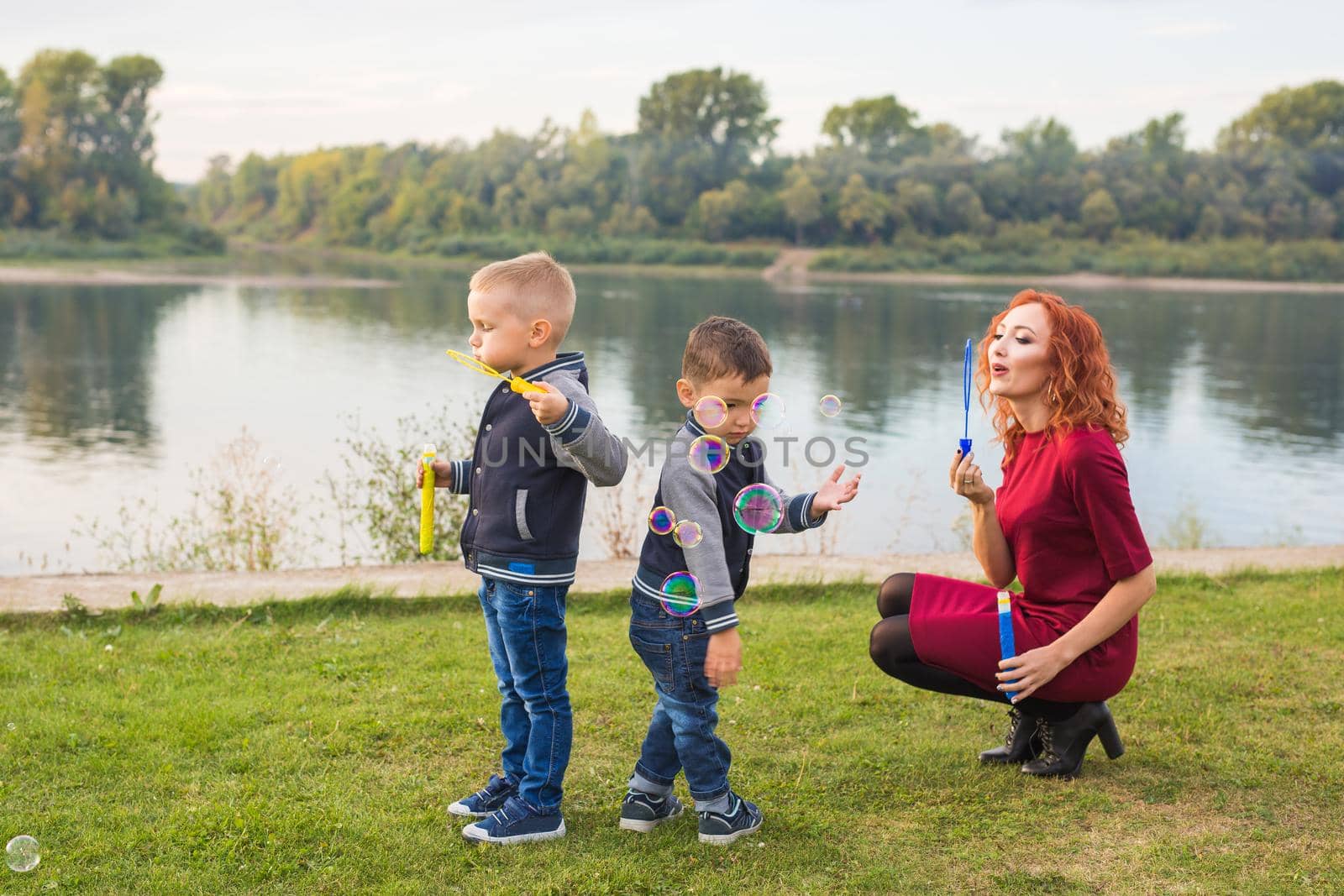 Family and nature concept - Mother and their children playing with colorful soap bubbles by Satura86