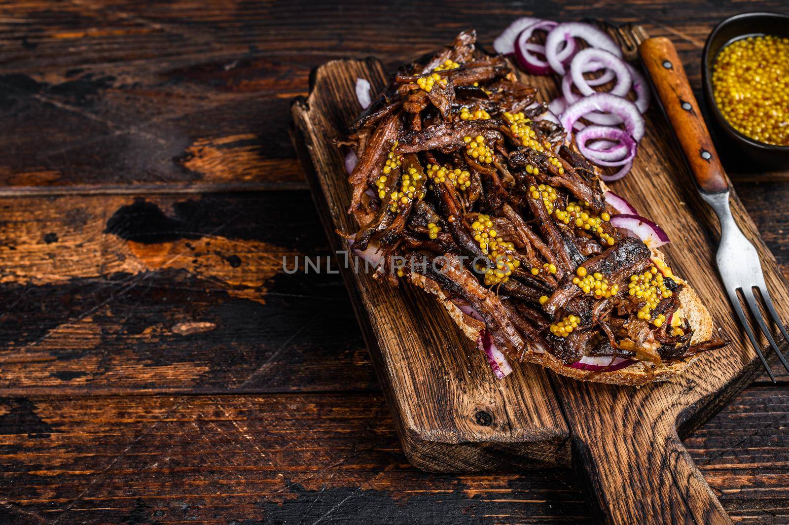 BBQ Texas Sandwich with slow roasted brisket beef meat. Dark wooden background. Top view. Copy space.