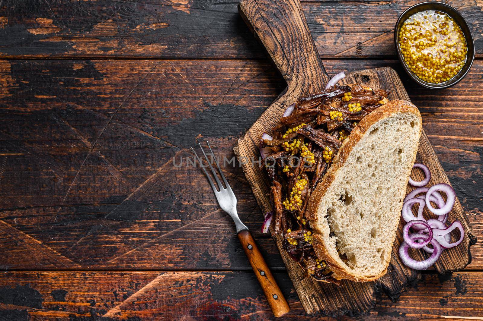 BBQ Texas Sandwich with slow roasted brisket beef meat. Dark wooden background. Top view. Copy space.