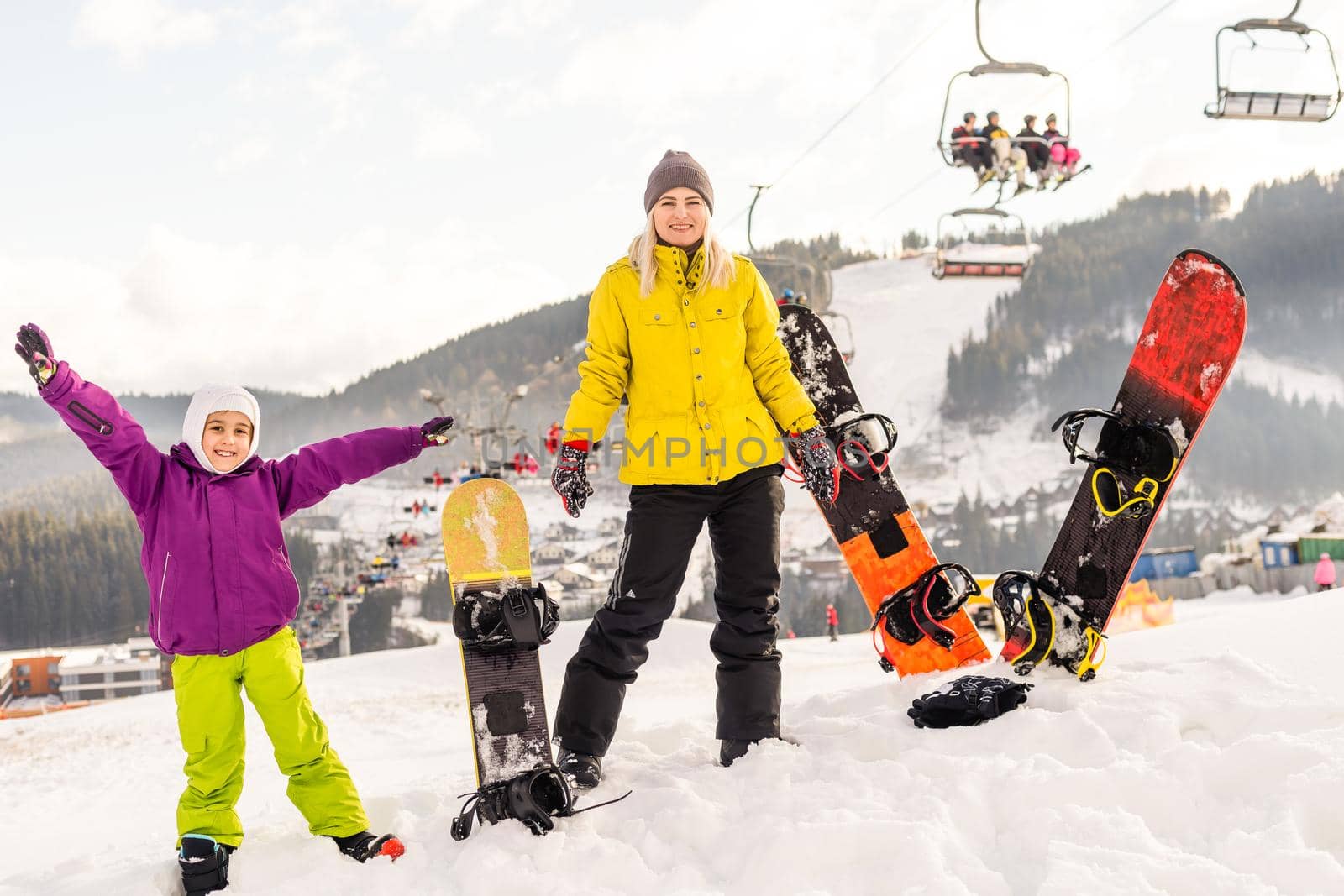 mother and daughter with snowboards at winter resort
