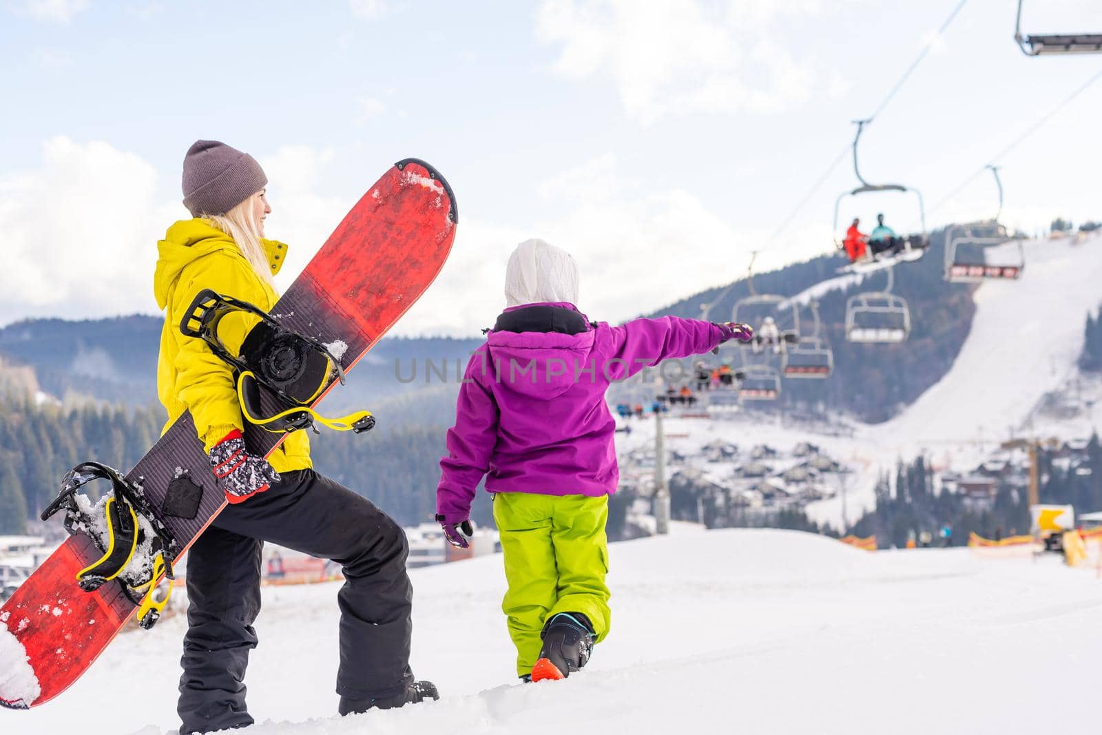 Mother and daughter with snowboards are playing in the snow