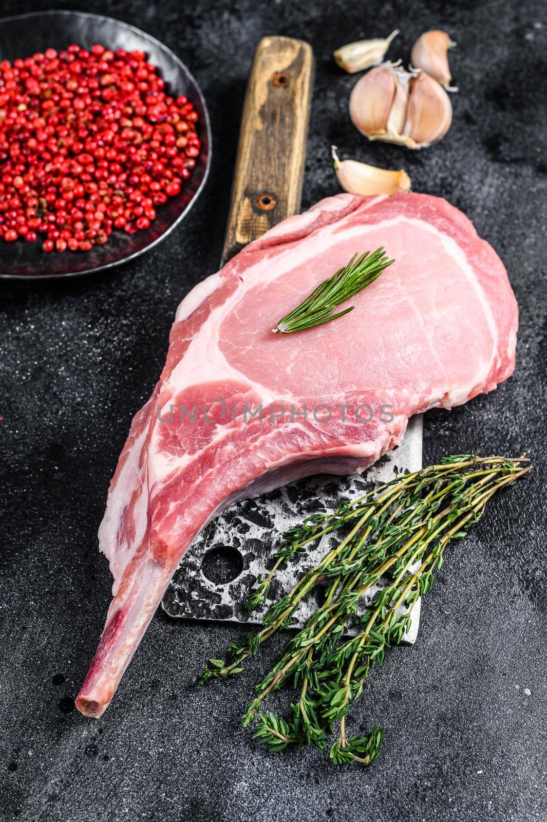 Raw tomahawk pork chop meat steak on a meat cleaver. Black background. Top view by Composter