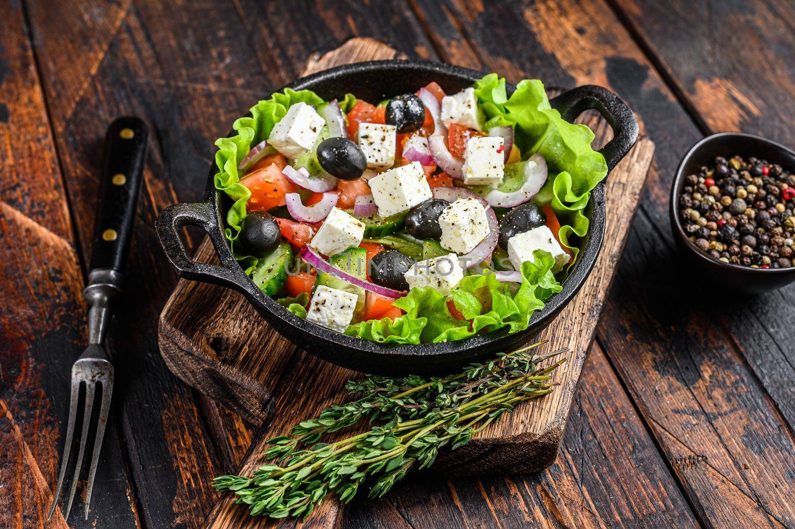 Greek salad with fresh vegetables and feta cheese in a pan. Dark Wooden background. Top view.