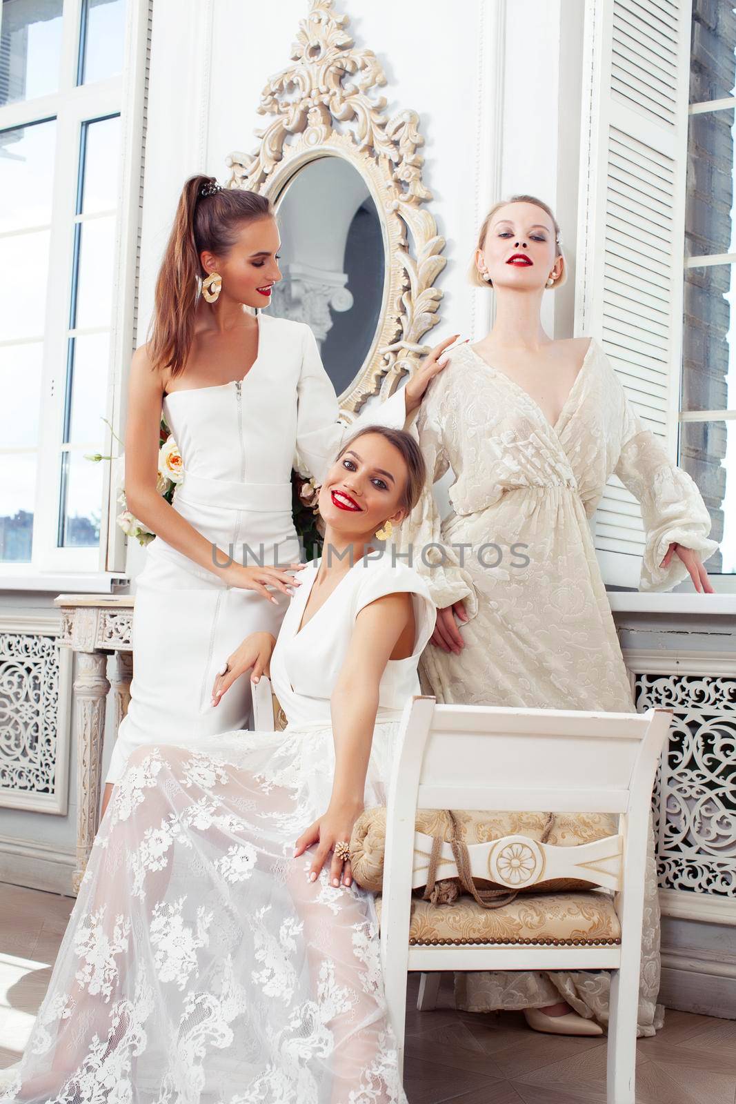 three young pretty lady in white lace fashion style dress posing in rich interior of royal hotel room, luxury lifestyle people concept, bride on wedding day closeup