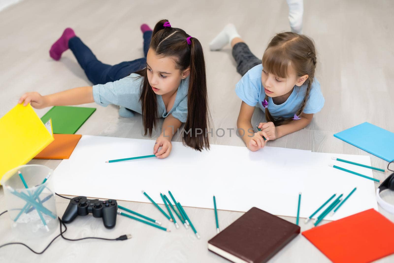 Cute children are painting and smiling while lying on the floor at home