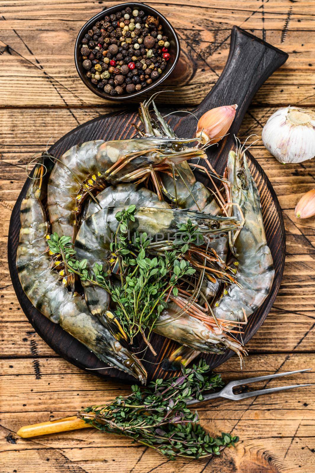 Raw black tiger shrimps prawns on a cutting board with herbs. wooden background. Top view by Composter