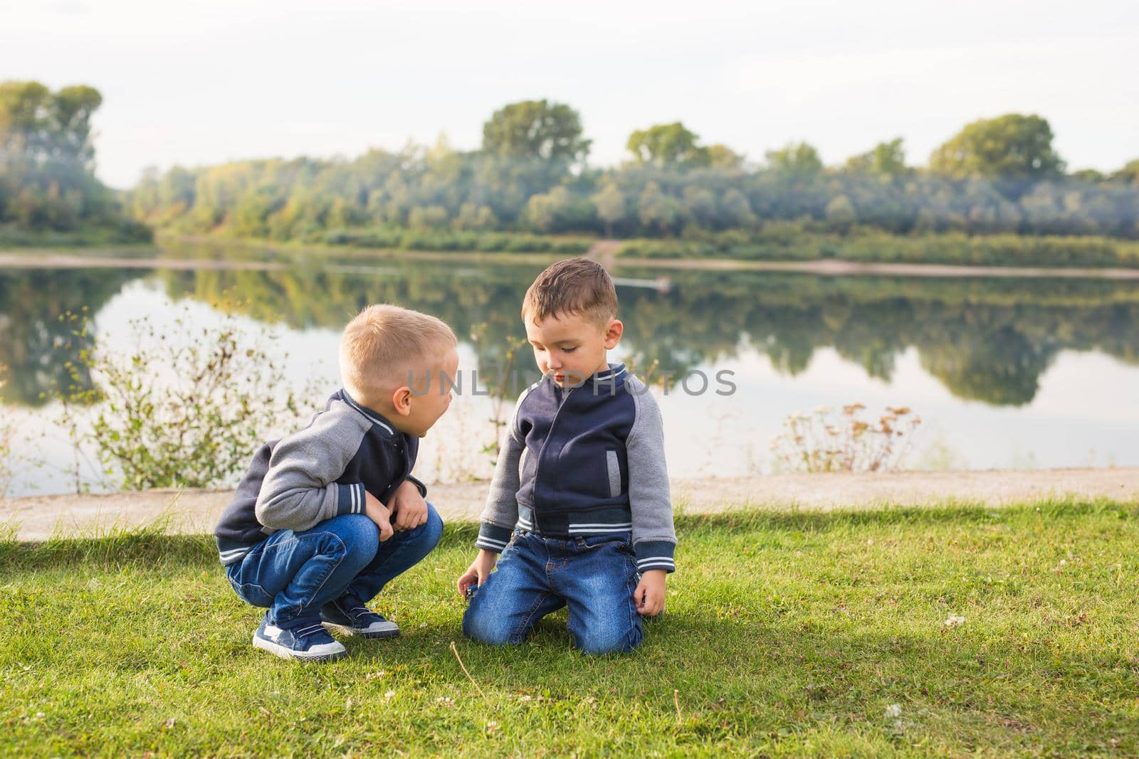 Children and nature concept - Two brothers sitting on the grass over nature background by Satura86