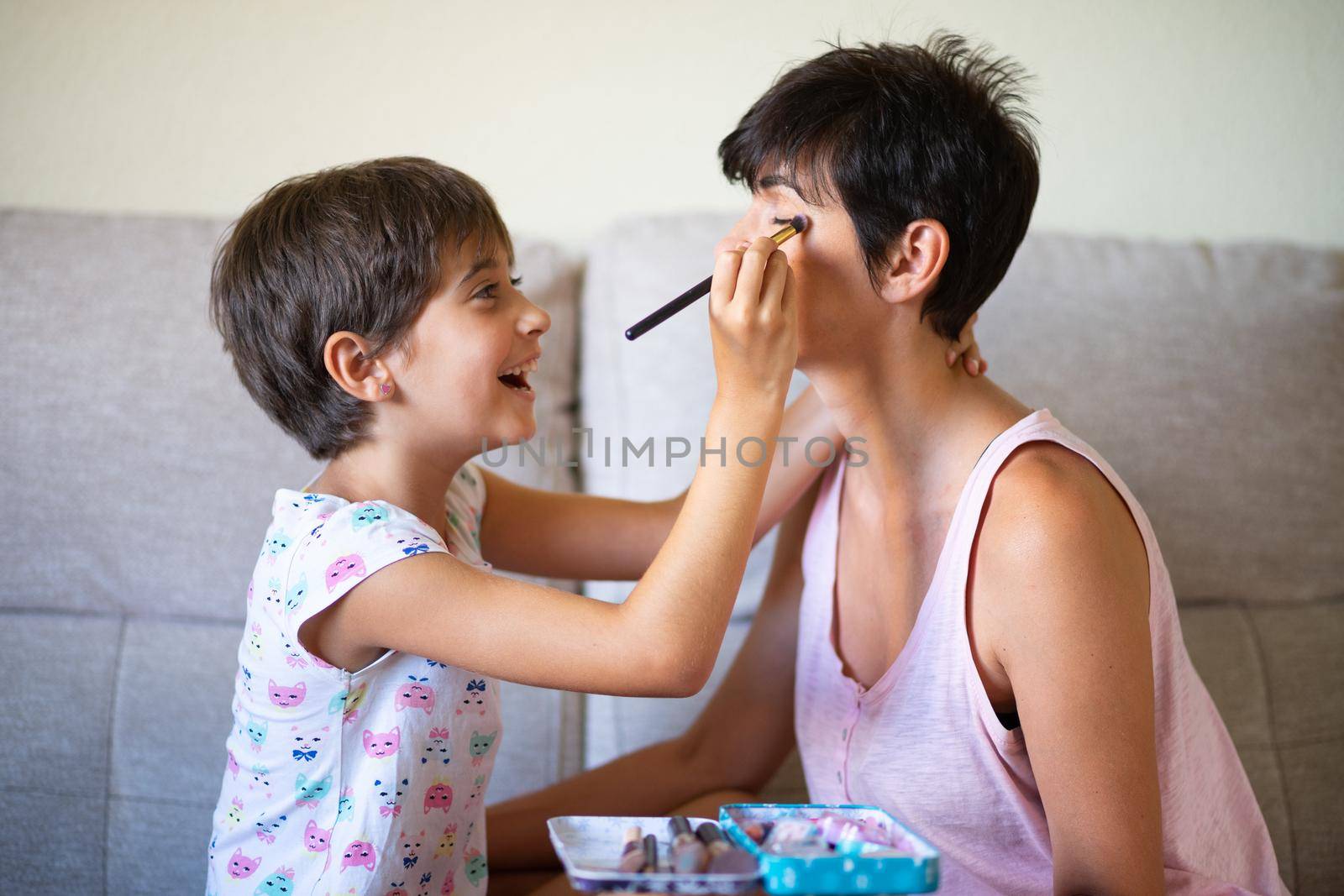 Mother and her little daughter doing make up for each other by javiindy