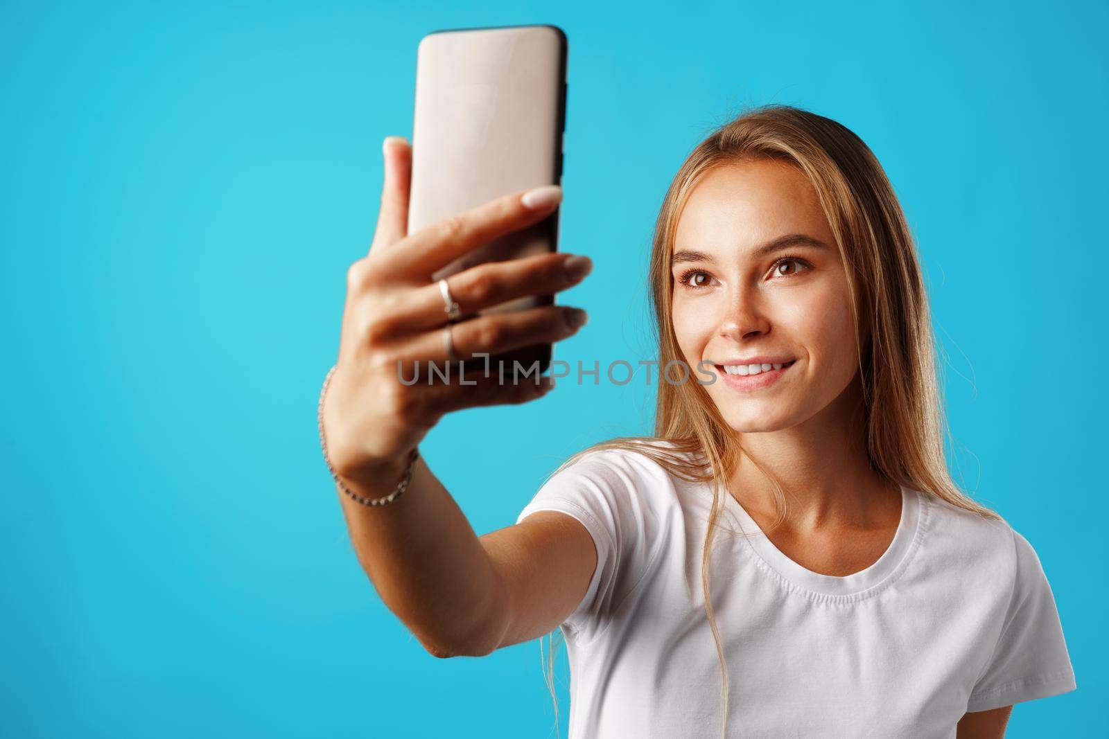 Happy casual young woman smiling and having a video call on smartphone