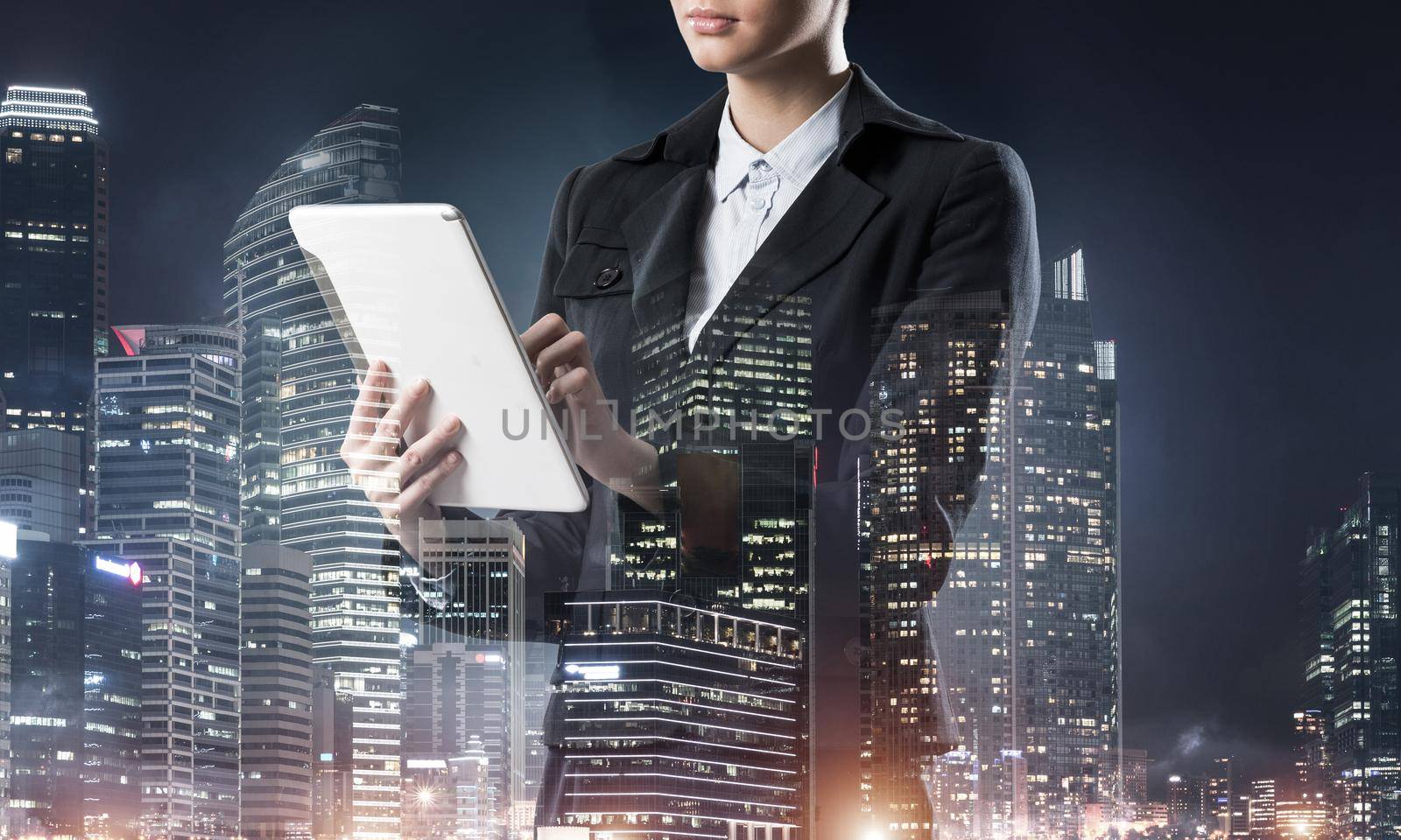 Businesswoman using tablet computer. Double exposure concept with night city and woman in business suit. Real estate investment. Digital technology in property management and development company.