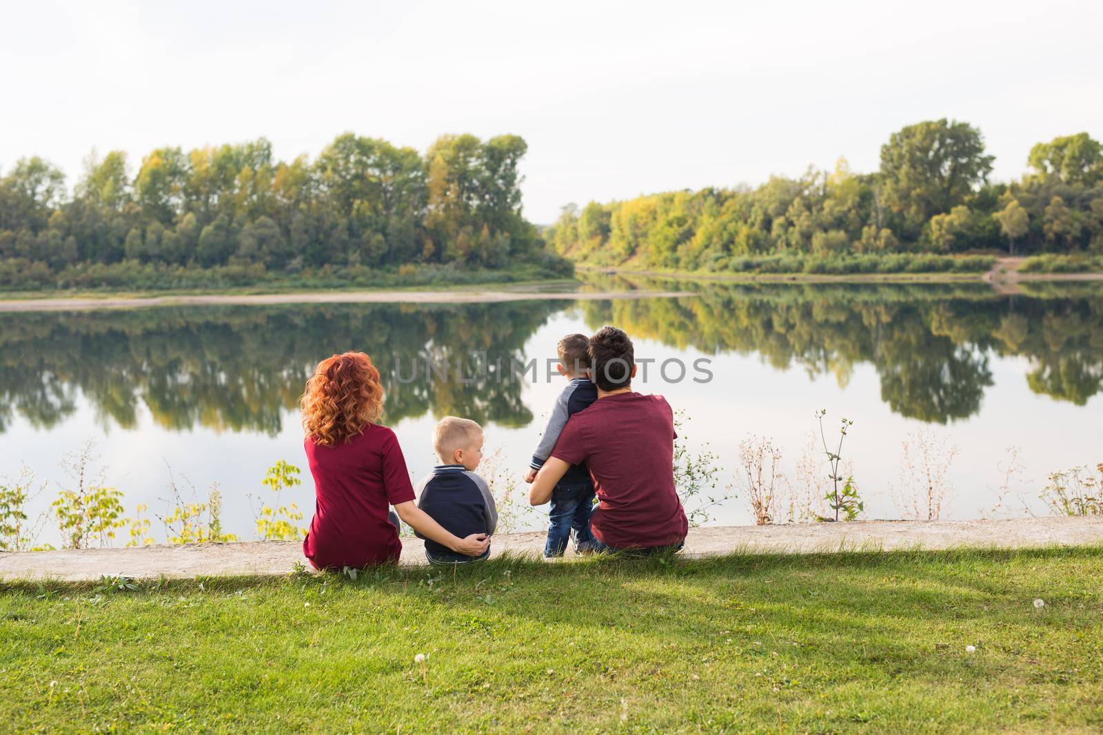 Childhood and nature concept - Family with little sons sitting on the green grass by Satura86