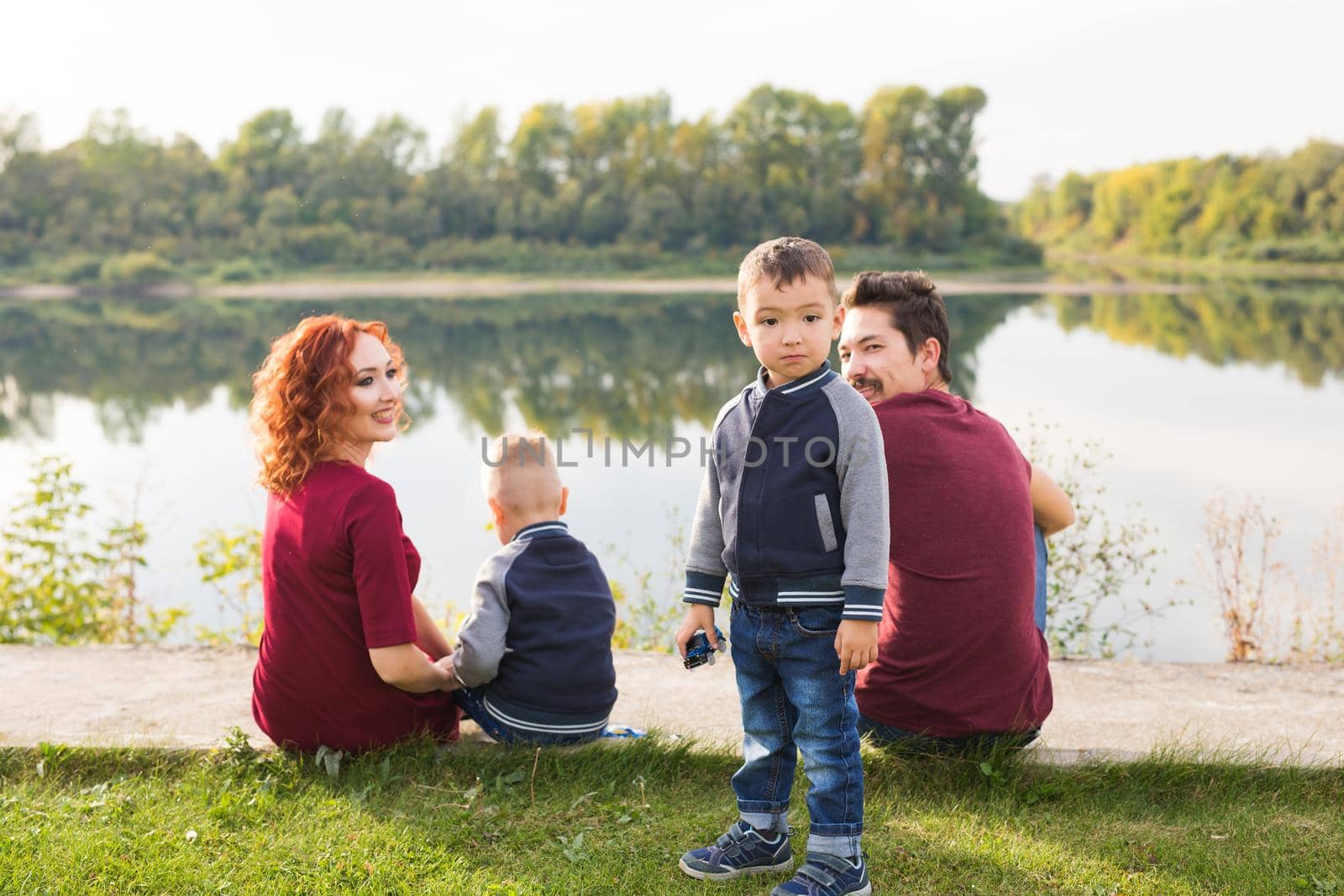 Parenthood, nature, people concept - family with two sons sitting near the lake by Satura86