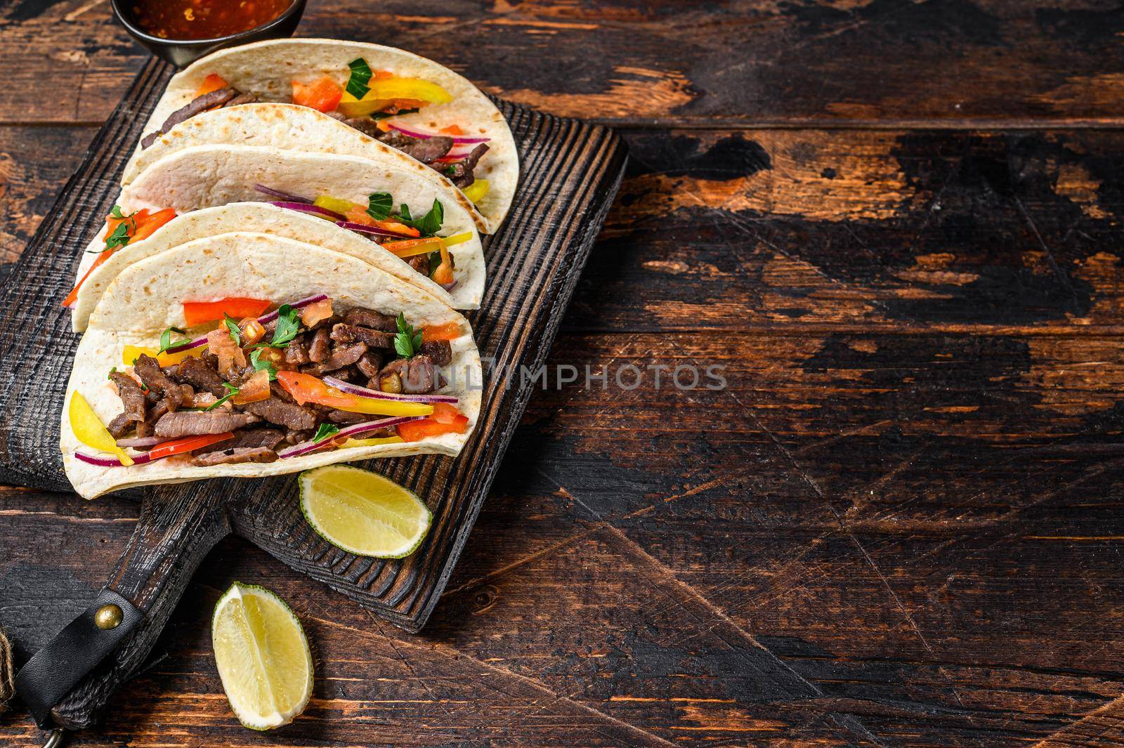 Tacos shells with pork meat, onion, tomato, sweet pepper and salsa. Mexican food. Dark wooden background. Top view. Copy space by Composter