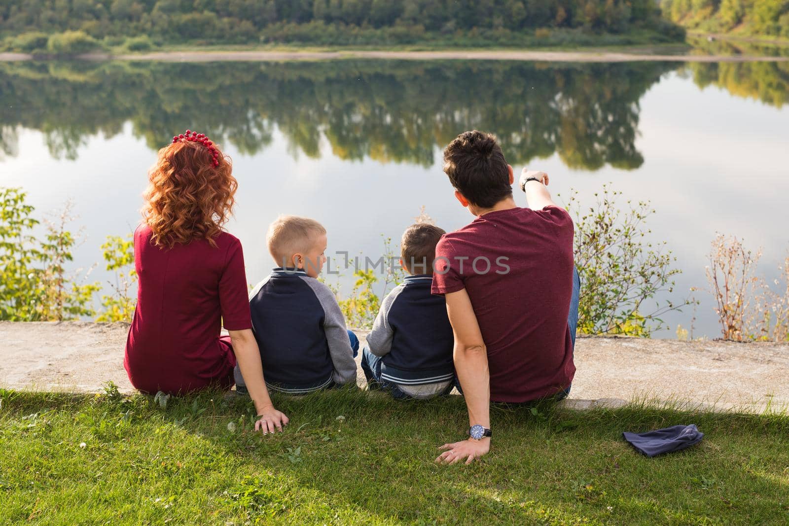 Childhood and nature concept - Family with little sons sitting on the green grass.