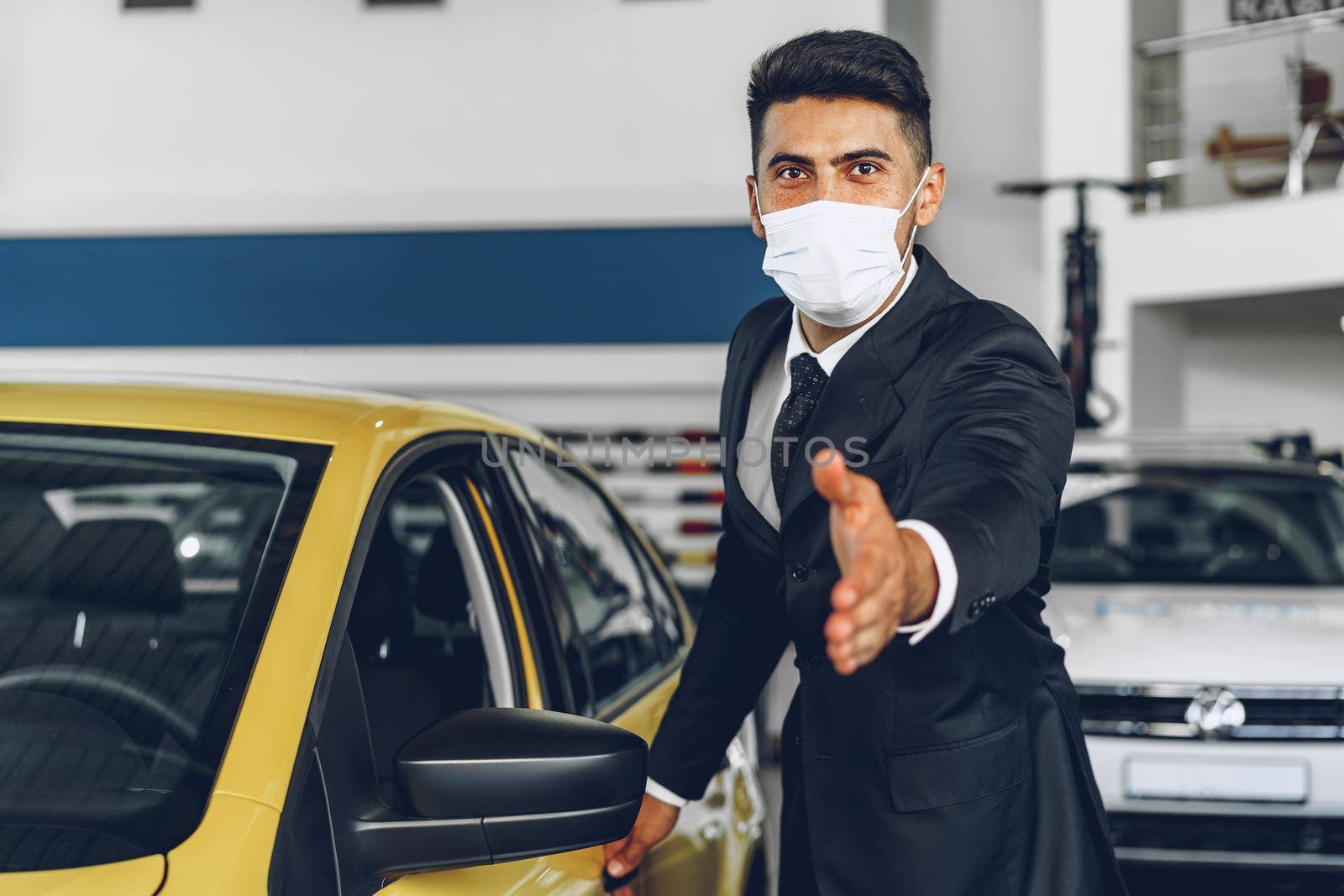 Man car dealer wearing protective medical mask on his working place, coronavirus prevention concept