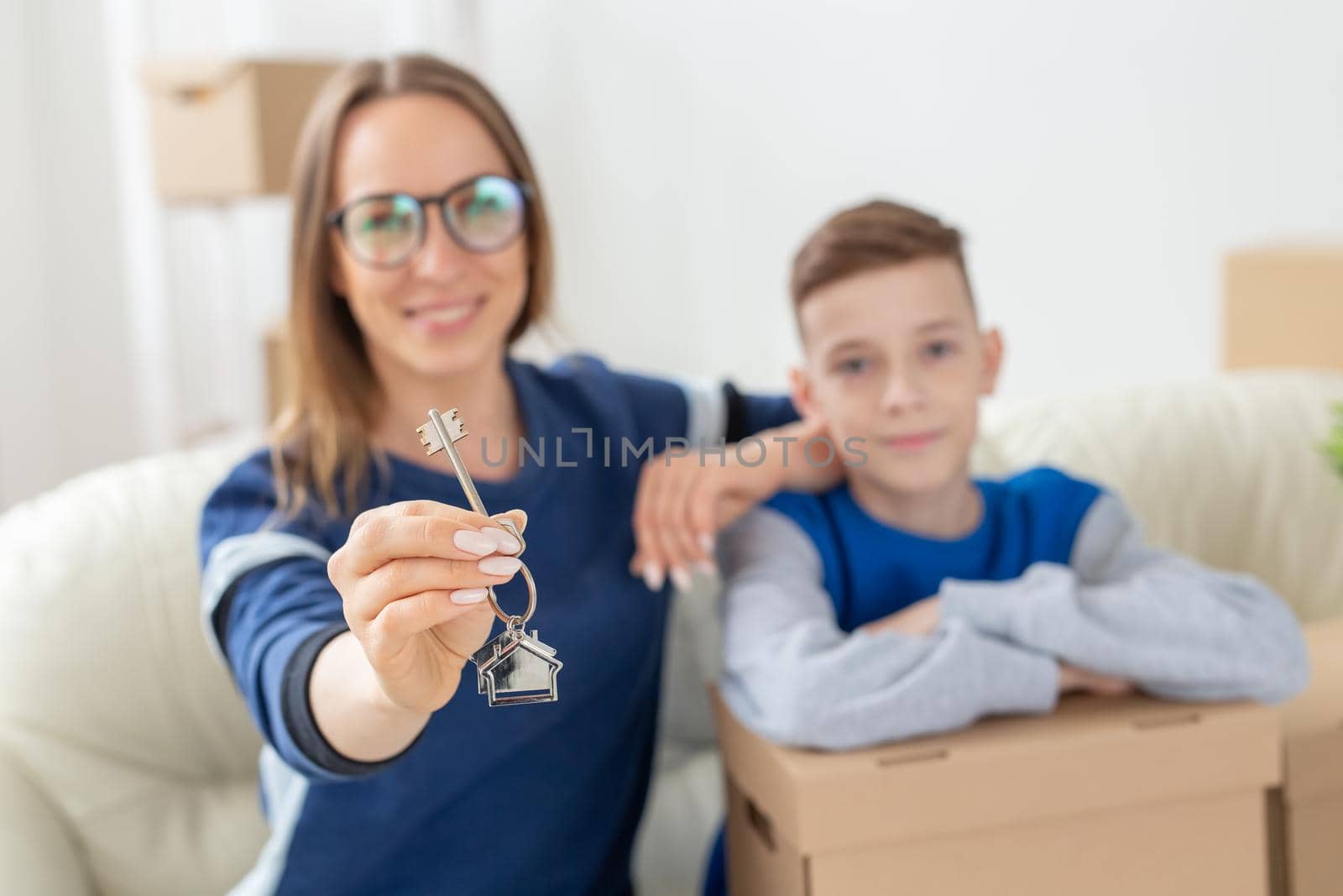 Blurry good looking mom and son are holding the keys to a new apartment after the housewarming. New concept and mortgage options for a young family