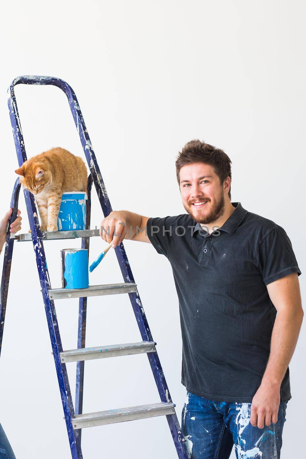 Renovation, redecoration and family concept - Young man stroking a cat during renovation in apartment.
