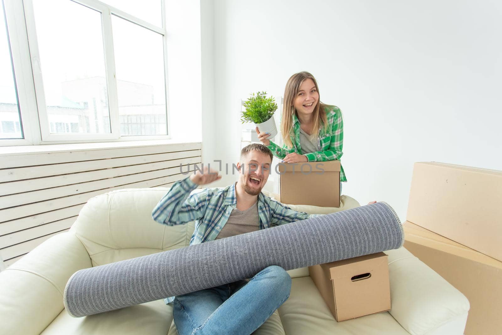 Satisfied cheerful young couple strong man and pretty woman holding their things in their hands sitting in the living room of a new apartment. Housewarming concept. by Satura86