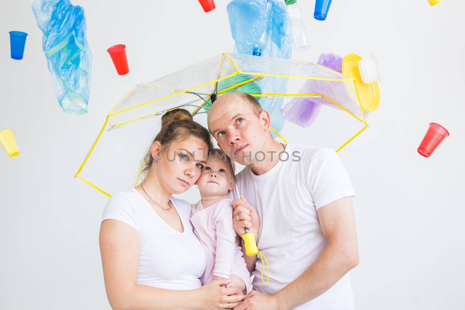 Plastic recycling problem, ecology and environmental disaster concept - family hiding from garbage under an umbrella on white background.