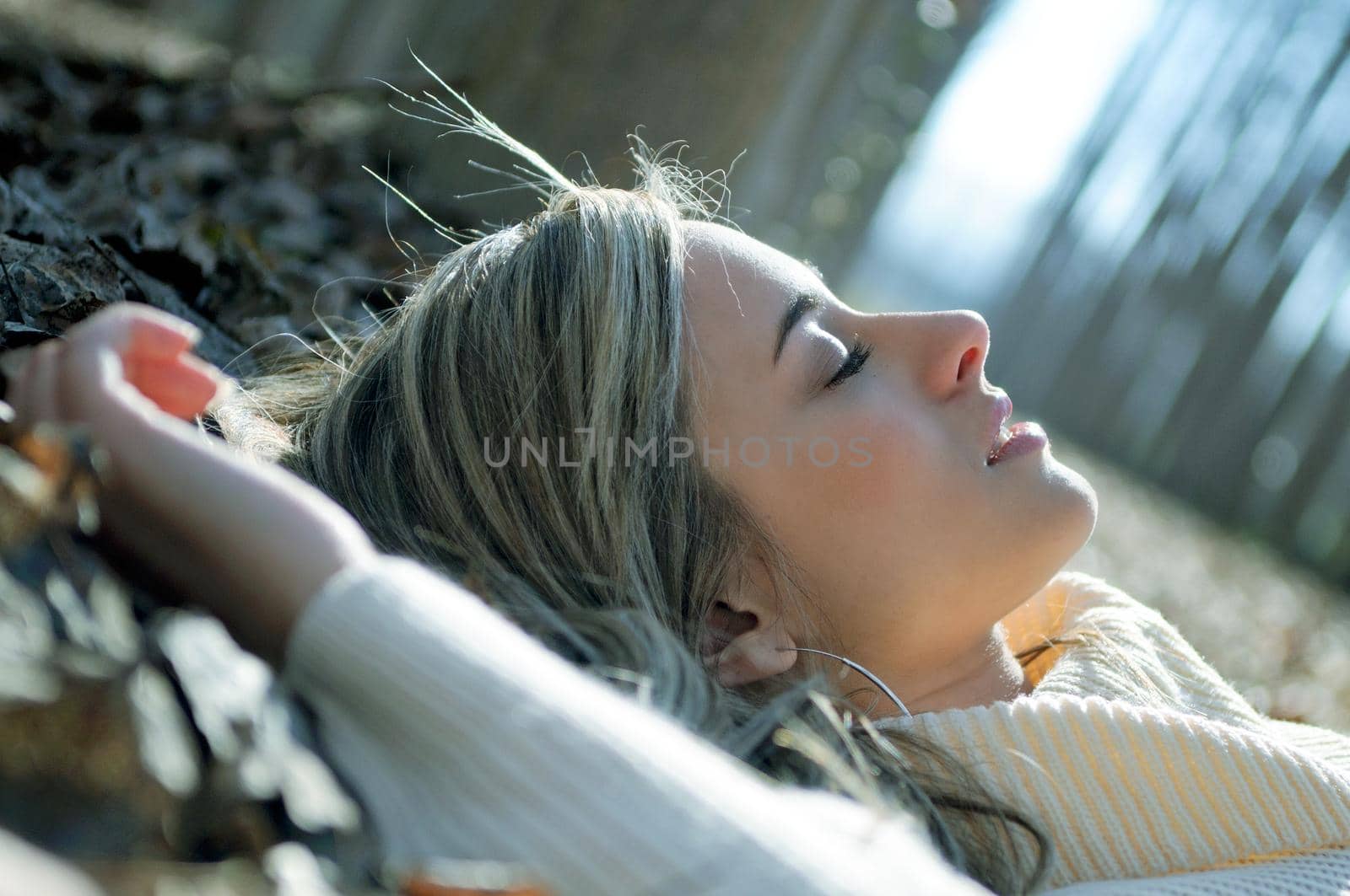 Beautiful blonde girl lying on leaves in a forest of poplars