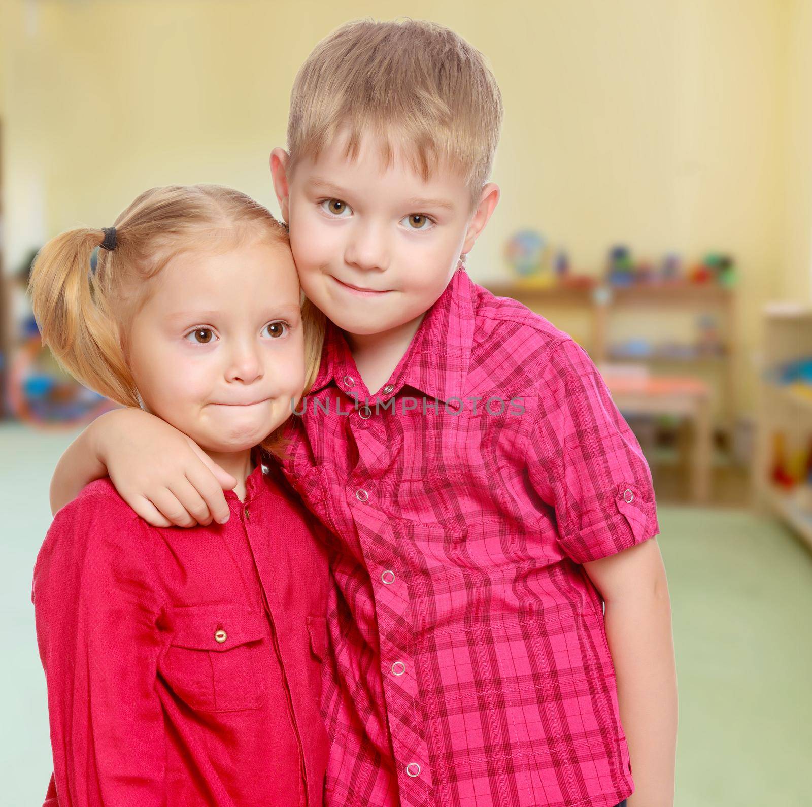 The concept of pre-school education of the child among their peers . on the background of the playroom with shelves for toys. Montessori.Little brother and sister cute hug.