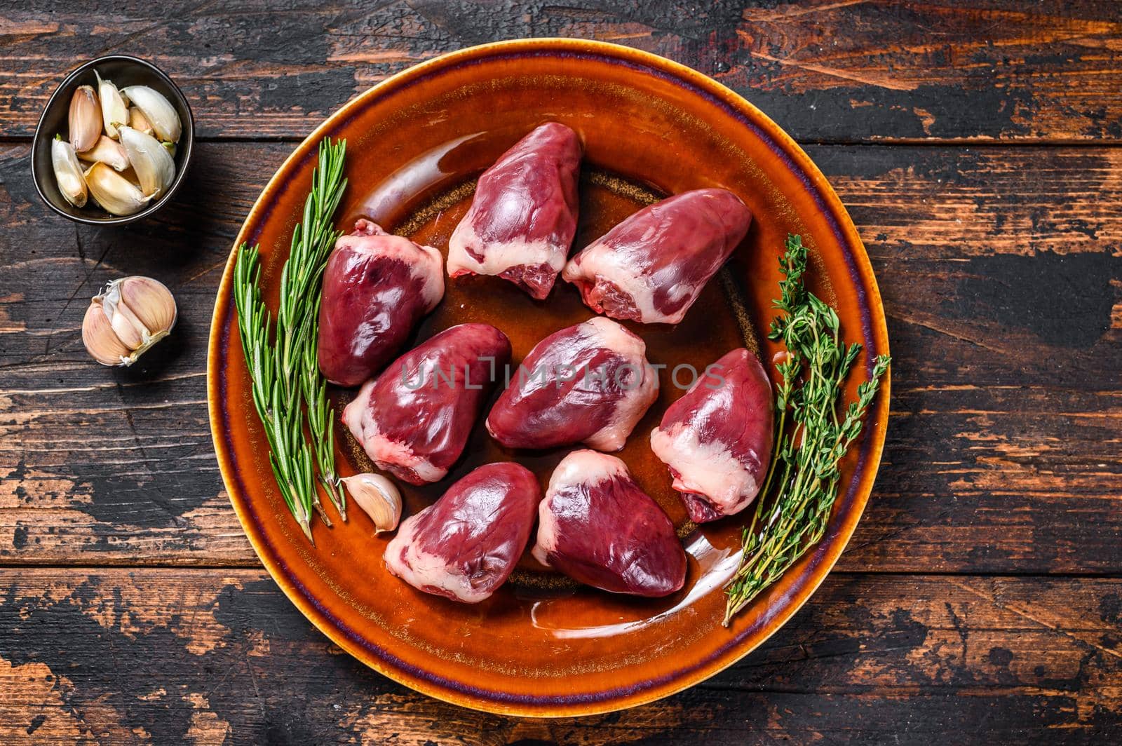 Fresh Raw turkey hearts offal giblets with thyme and rosemary. Dark wooden background. Top view by Composter