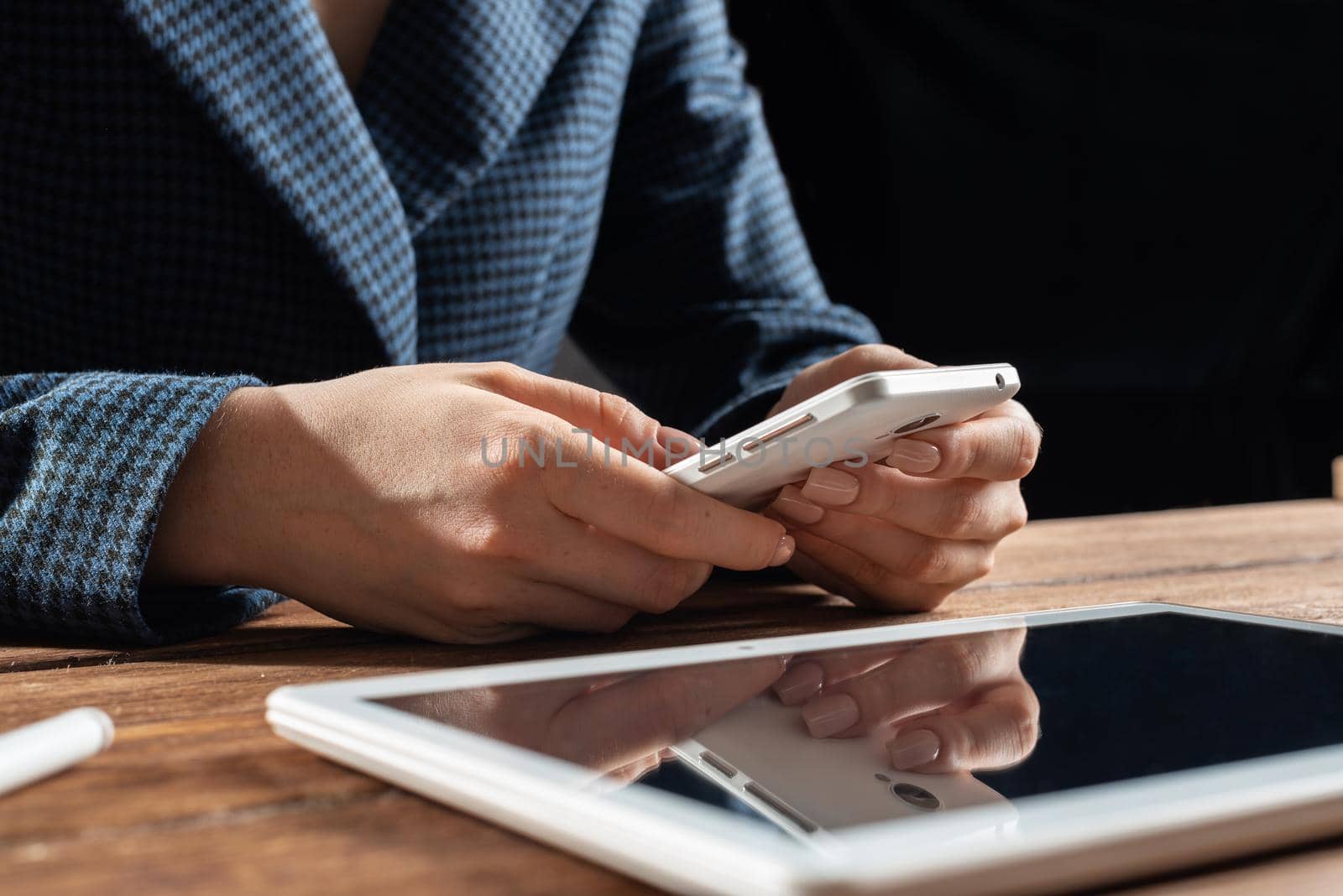 Businesswoman using mobile phone at desk. Close up woman hands and tablet computer. Mobile communication concept with chatting woman. Digital technology in strategy planning and company management