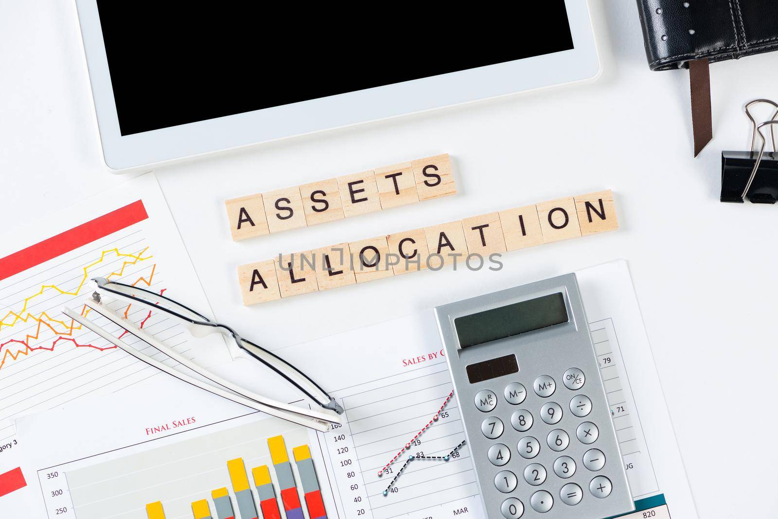 Asset allocation concept with letters on cubes. Still life of office workplace with supplies. Flat lay white surface with tablet computer, calculator and glasses. Investment strategy and planning.