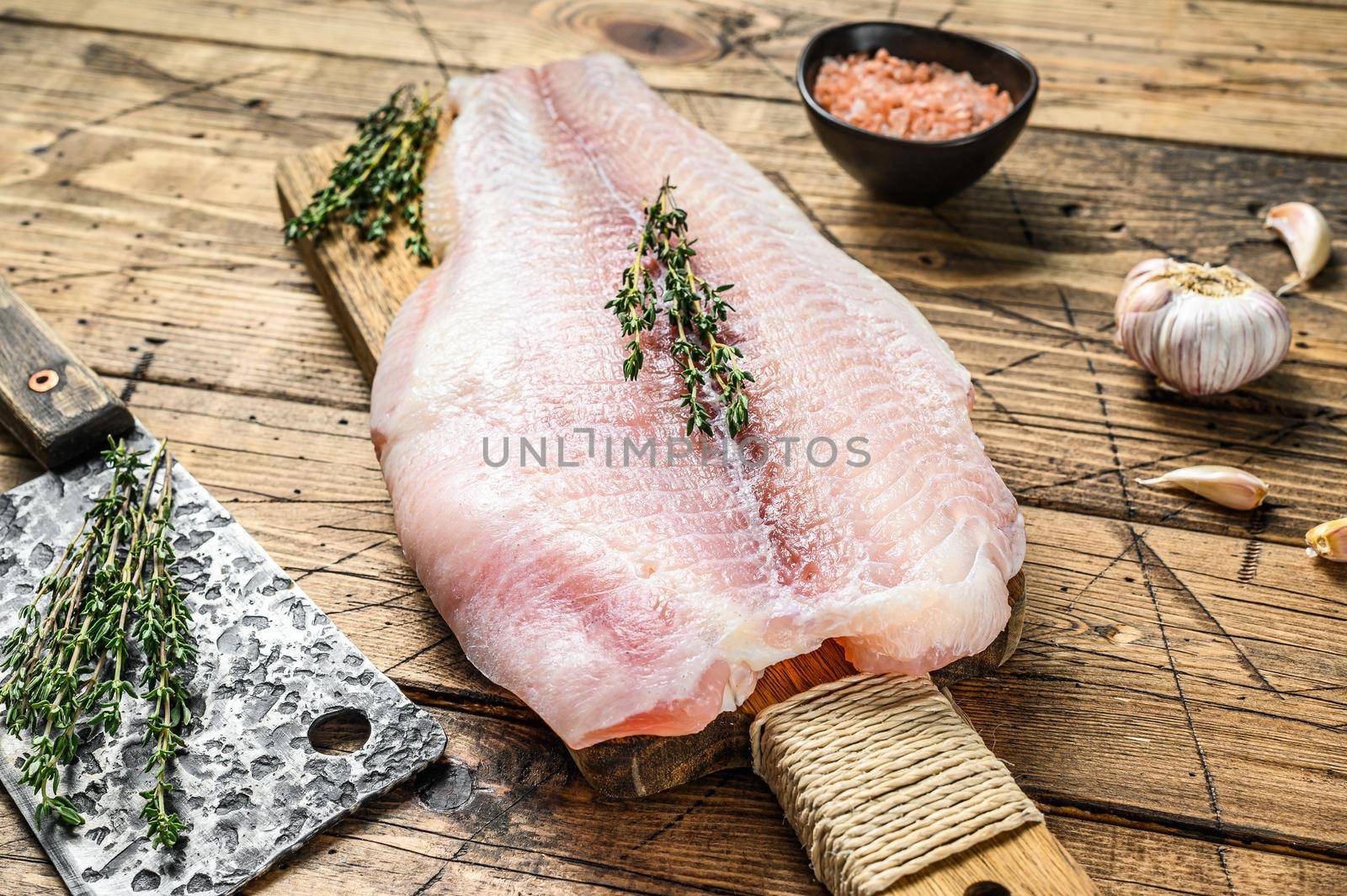 Raw fillet of pangasius fish on a cutting board. Wooden background. Top view by Composter