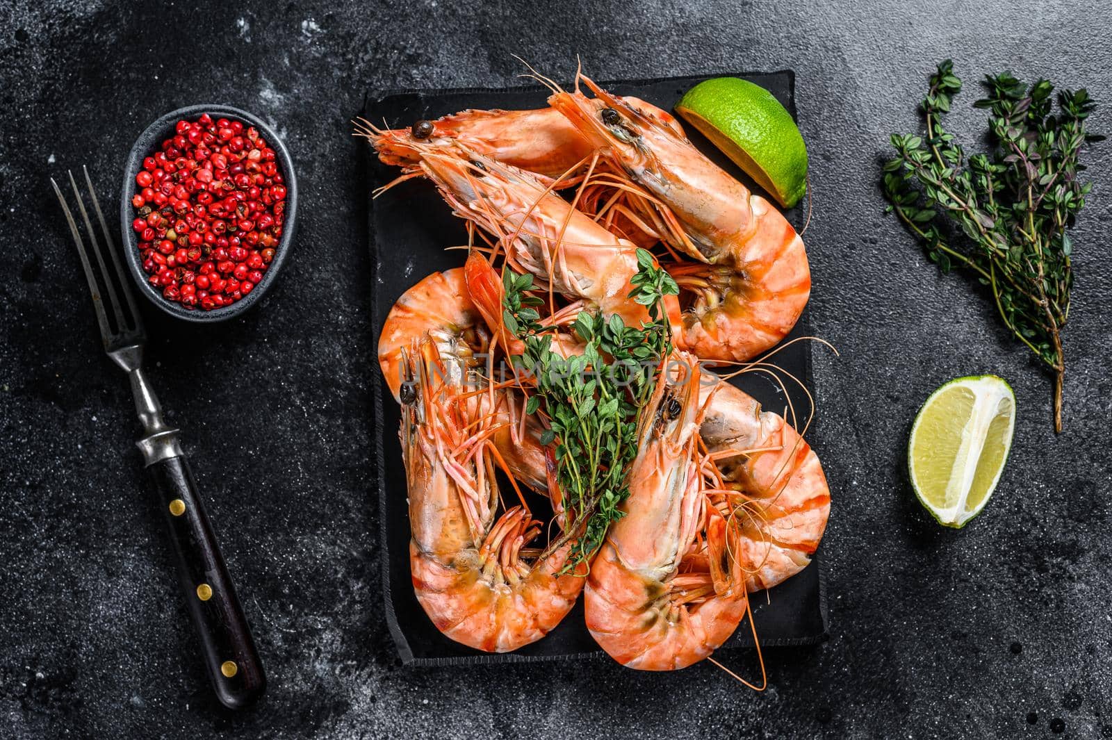 Red Langostino shrimps Prawns on a marble board. Black background. Top view by Composter