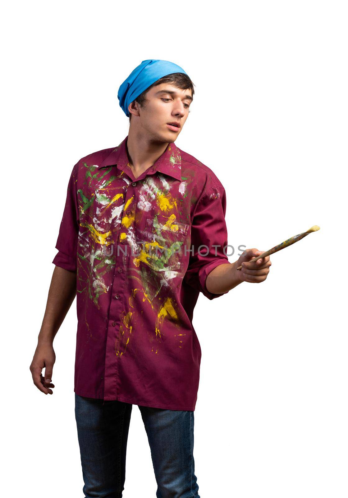 Young male painter artist holding paintbrush. Portrait of painter in dirty shirt and bandana standing on white background. Creative hobby and artistic occupation. Art school courses concept.