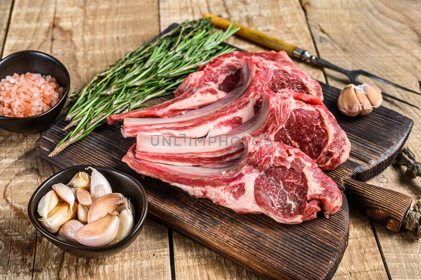 Lamb raw cutlets chops with salt, pepper and garlic. wooden background. Top view.