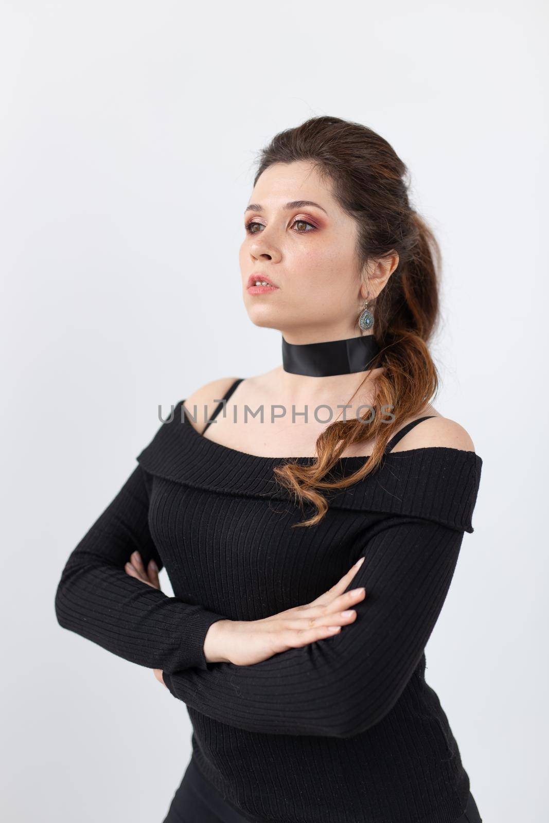 Portrait of a beautiful romantic young woman with black ribbon on the neck posing on a white background. Advertising space. Beauty concept