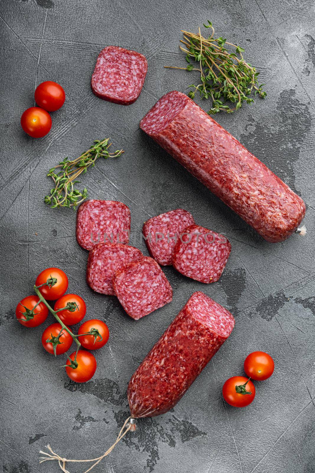 Slices of salami with vegetables set, on gray stone table background, top view flat lay