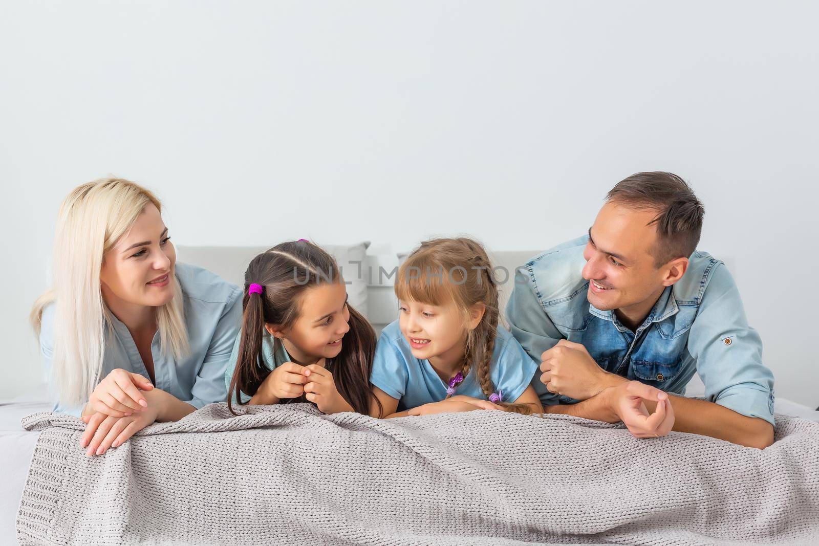 Happy family lying on a bed together in the bedroom by Andelov13