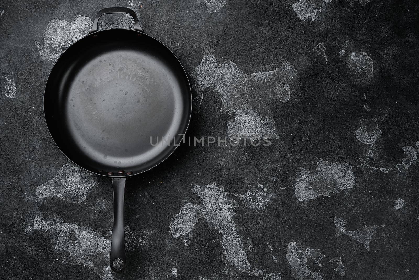 Used old empty frying pan set with copy space for text or food with copy space for text or food, top view flat lay, on black dark stone table background