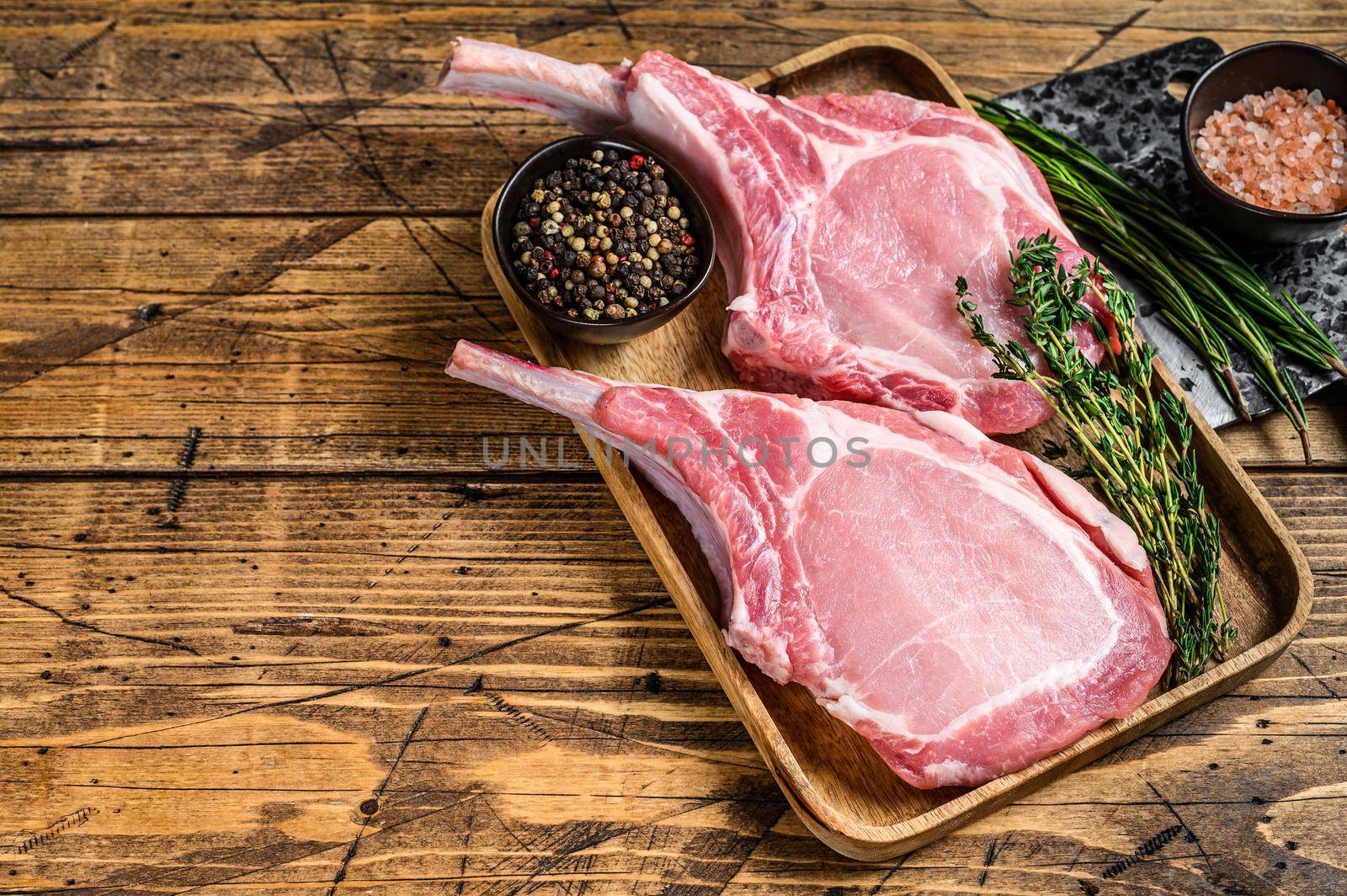 Fresh raw pork loin chops with pepper and salt. wooden background. Top view.