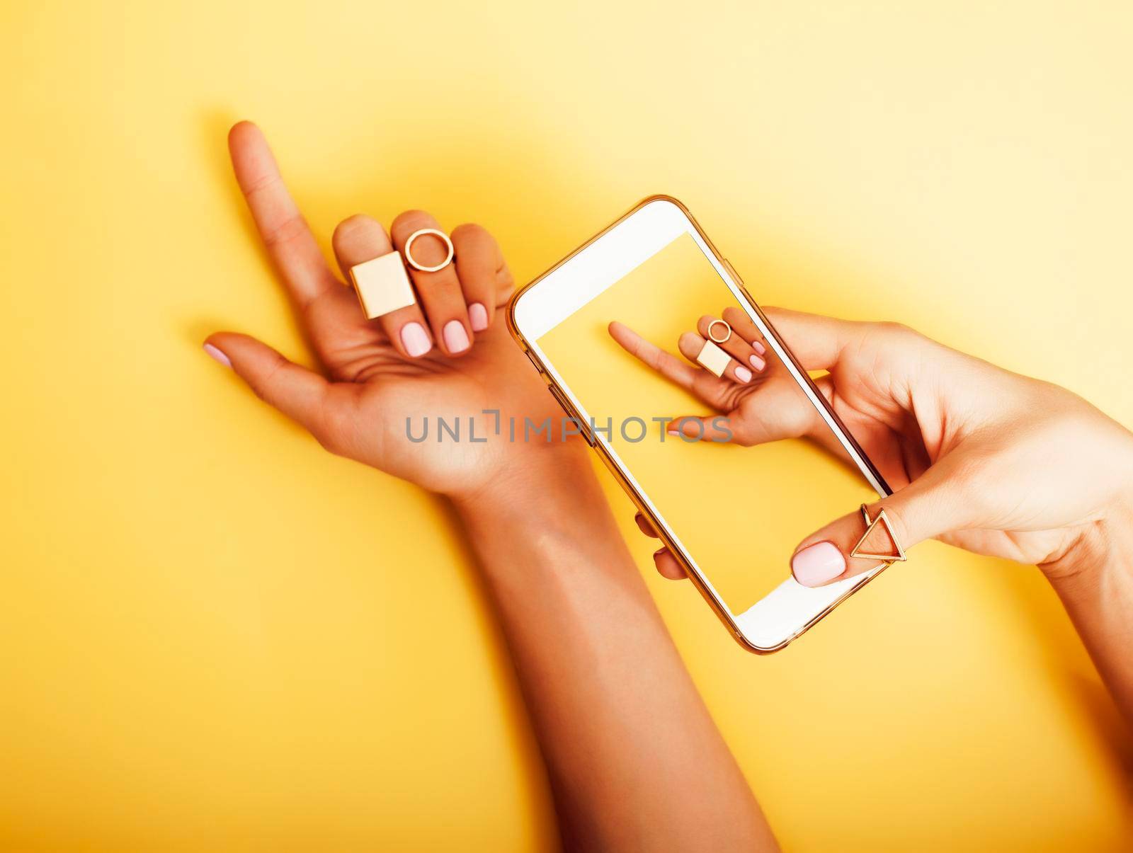 womans hand taking picture of her new manicure with fashion jewellery on her phone, girls stuff concept by JordanJ