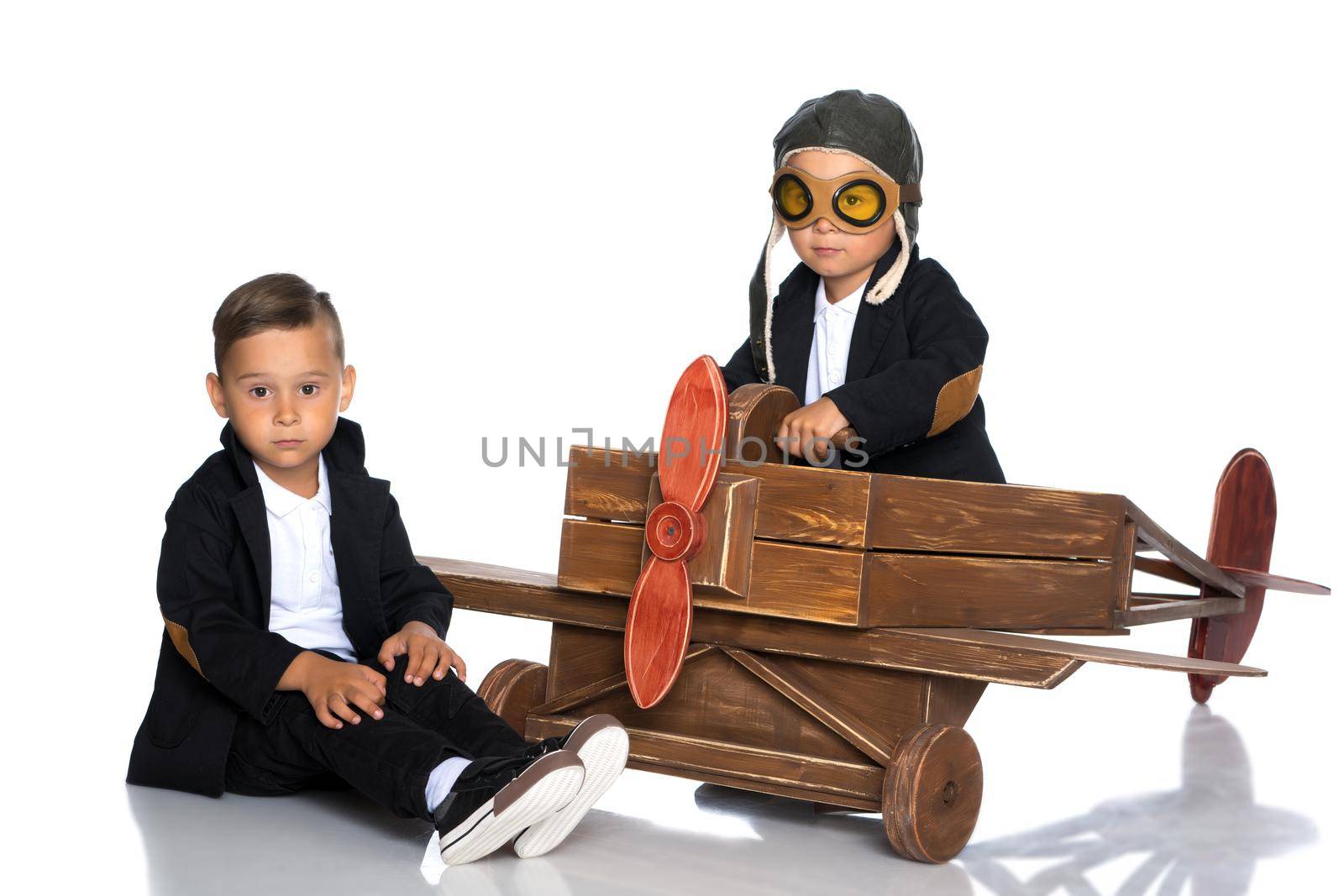 Two cute little boys are playing with a toy airplane. Isolated on white background.