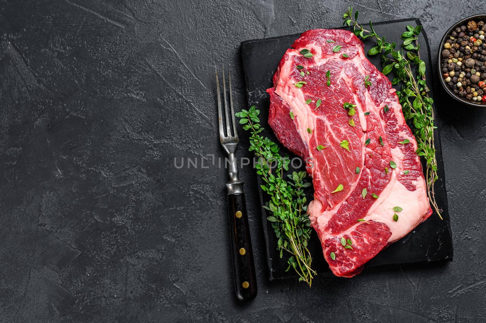 Raw Organic chuck eye roll meat steak cuts. Black background. Top view. Copy space by Composter