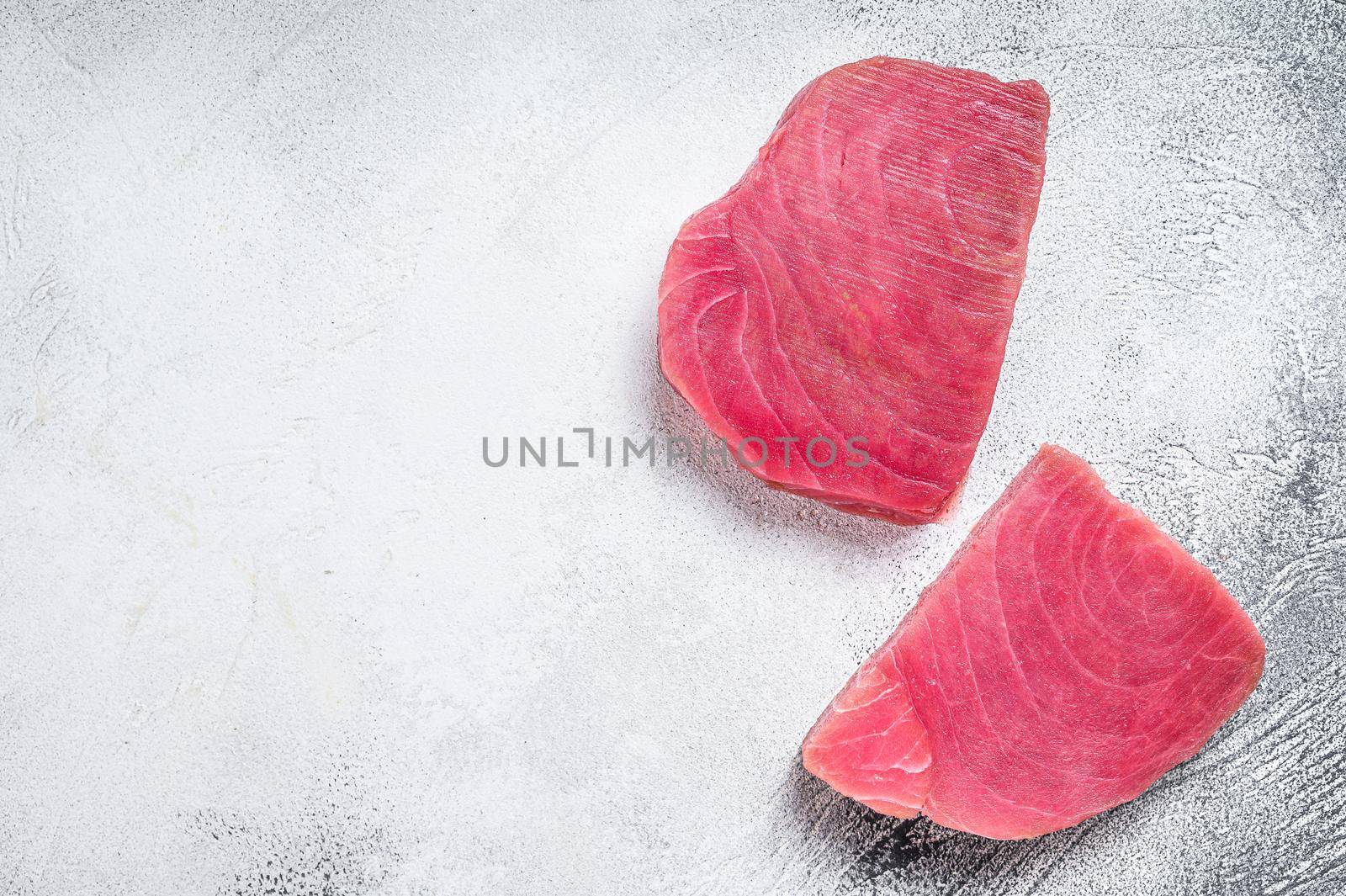 Two raw tuna steaks on rustic table. White background. Top view. Copy space by Composter