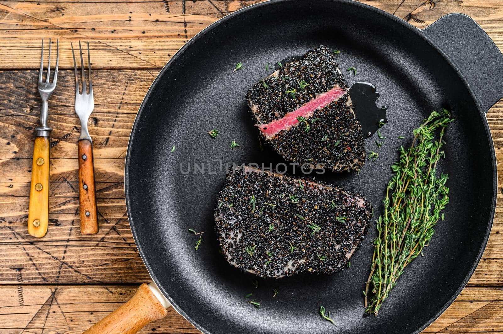 Grilled teriyaki tuna steak in a pan. Wooden background. Top view.