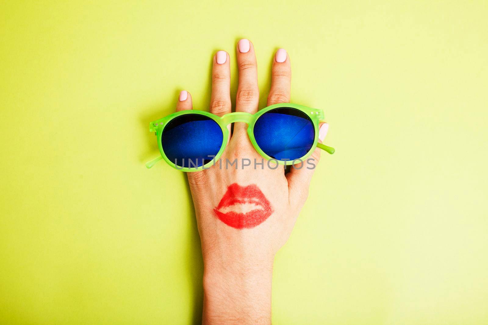 woman hand holding sunglasses on bright background, cosmetic summer vacation concept close up