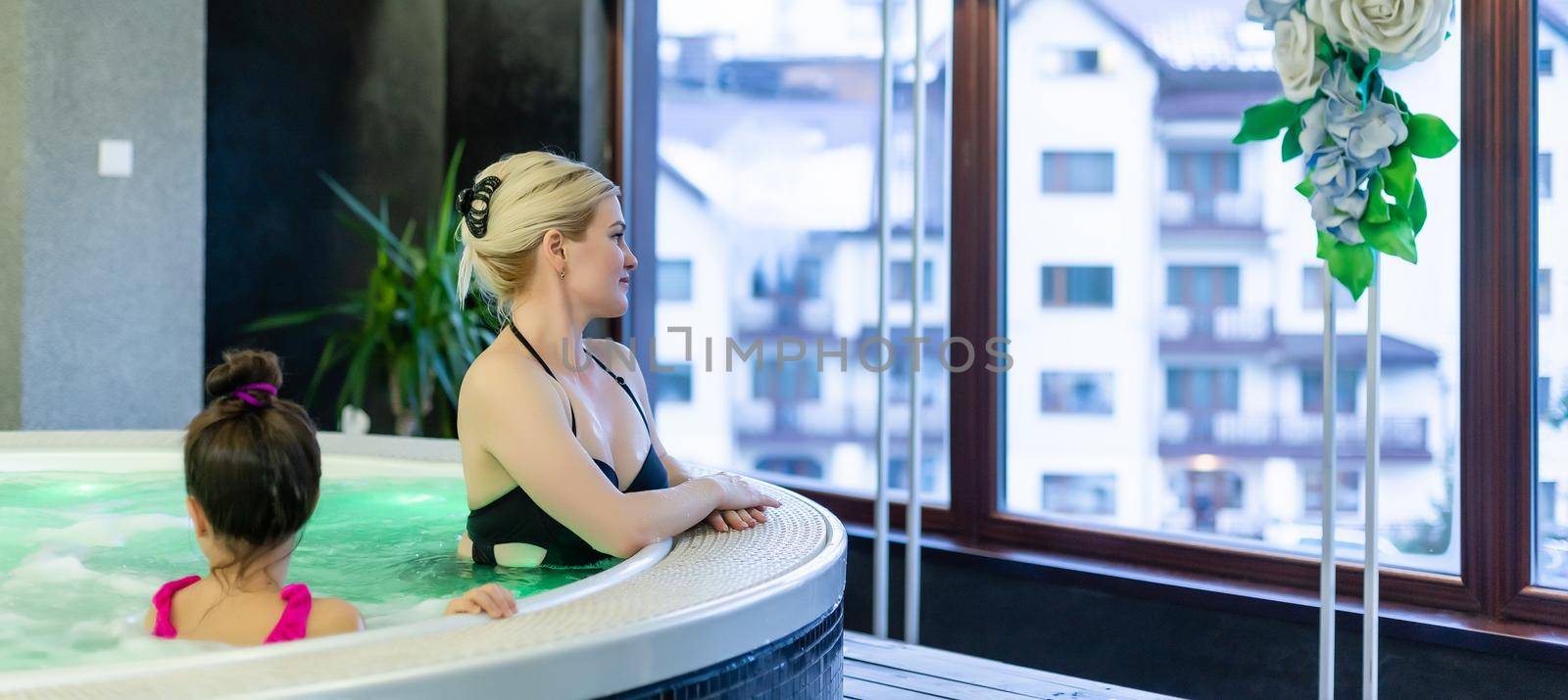 mother and daughter Relaxing By Swimming Pool