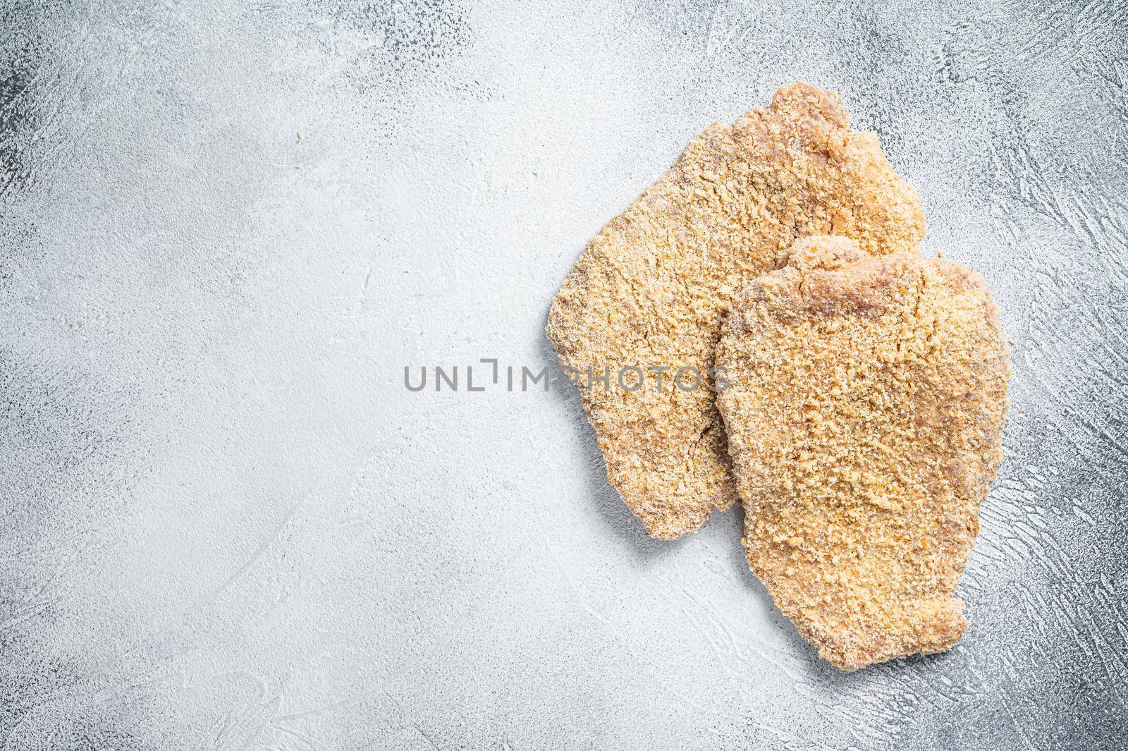 Raw chicken schnitzel Escalope in breadcrumbs. White background. Top view. Copy space by Composter