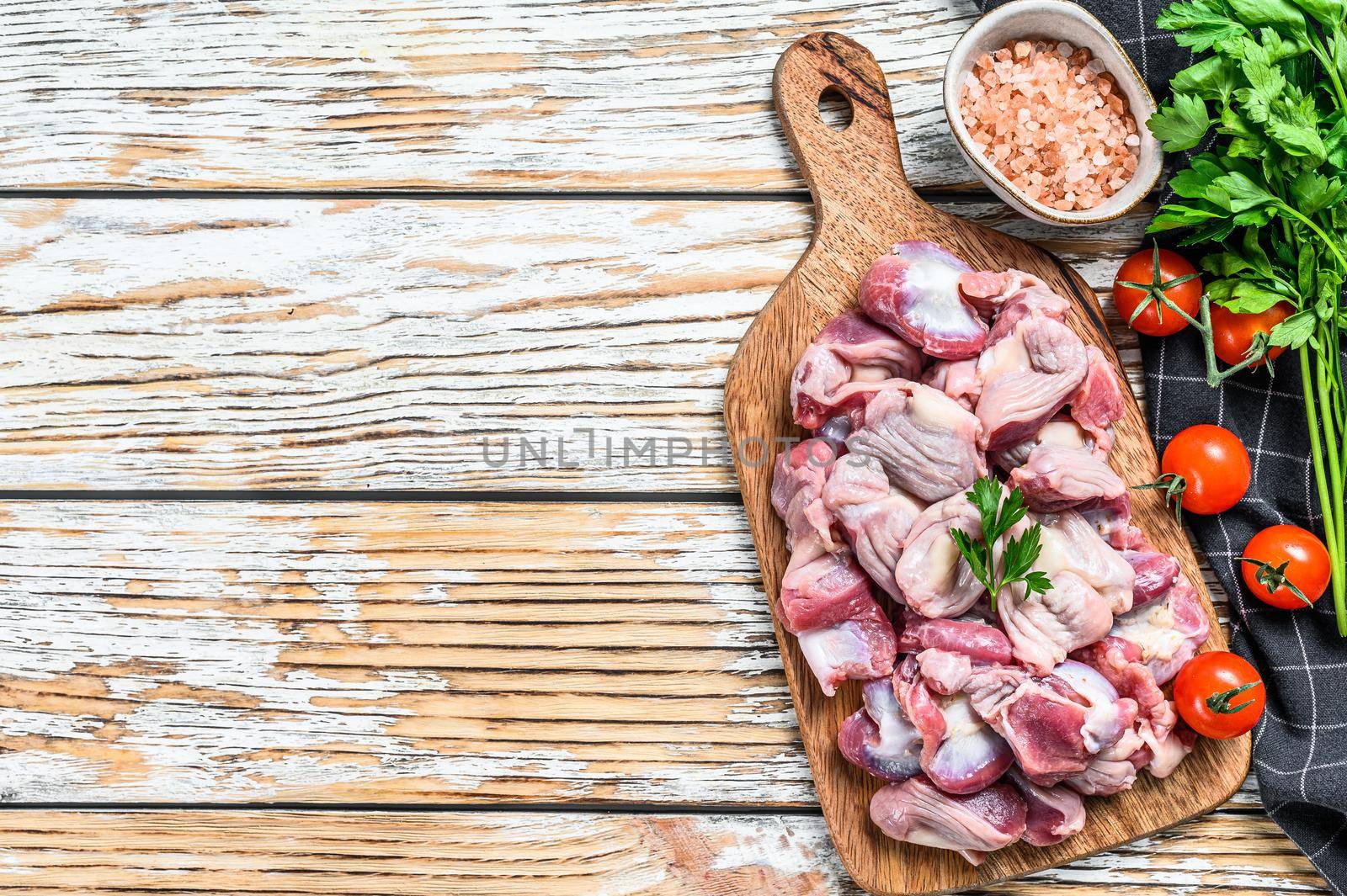 Raw uncooked chicken gizzards, stomach on a cutting board. wooden background. Top view. Copy space by Composter