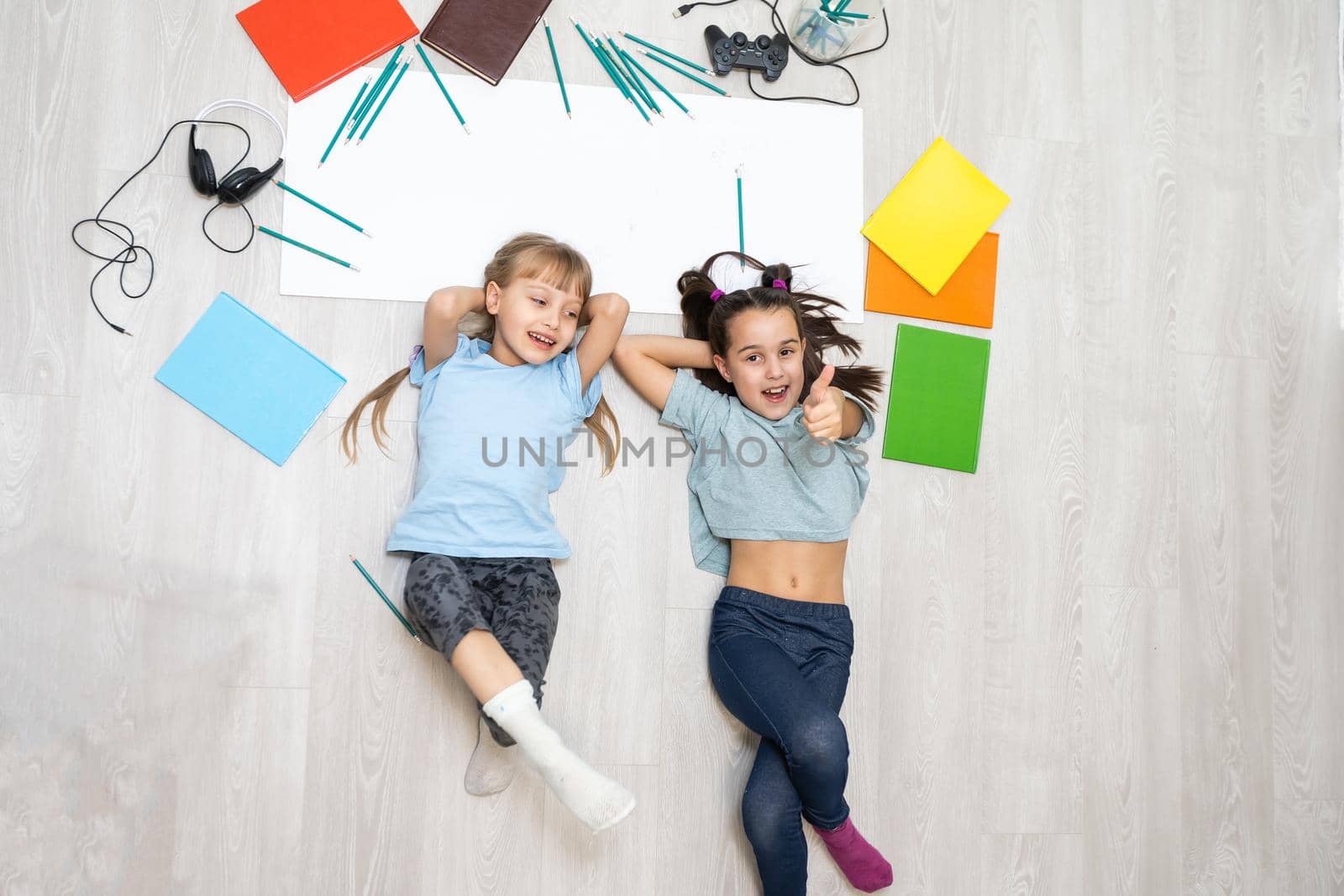 Cute children are painting and smiling while lying on the floor at home